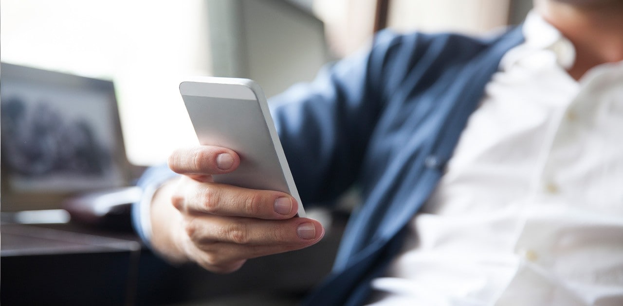 A man holding a smart phone while sitting at a desk