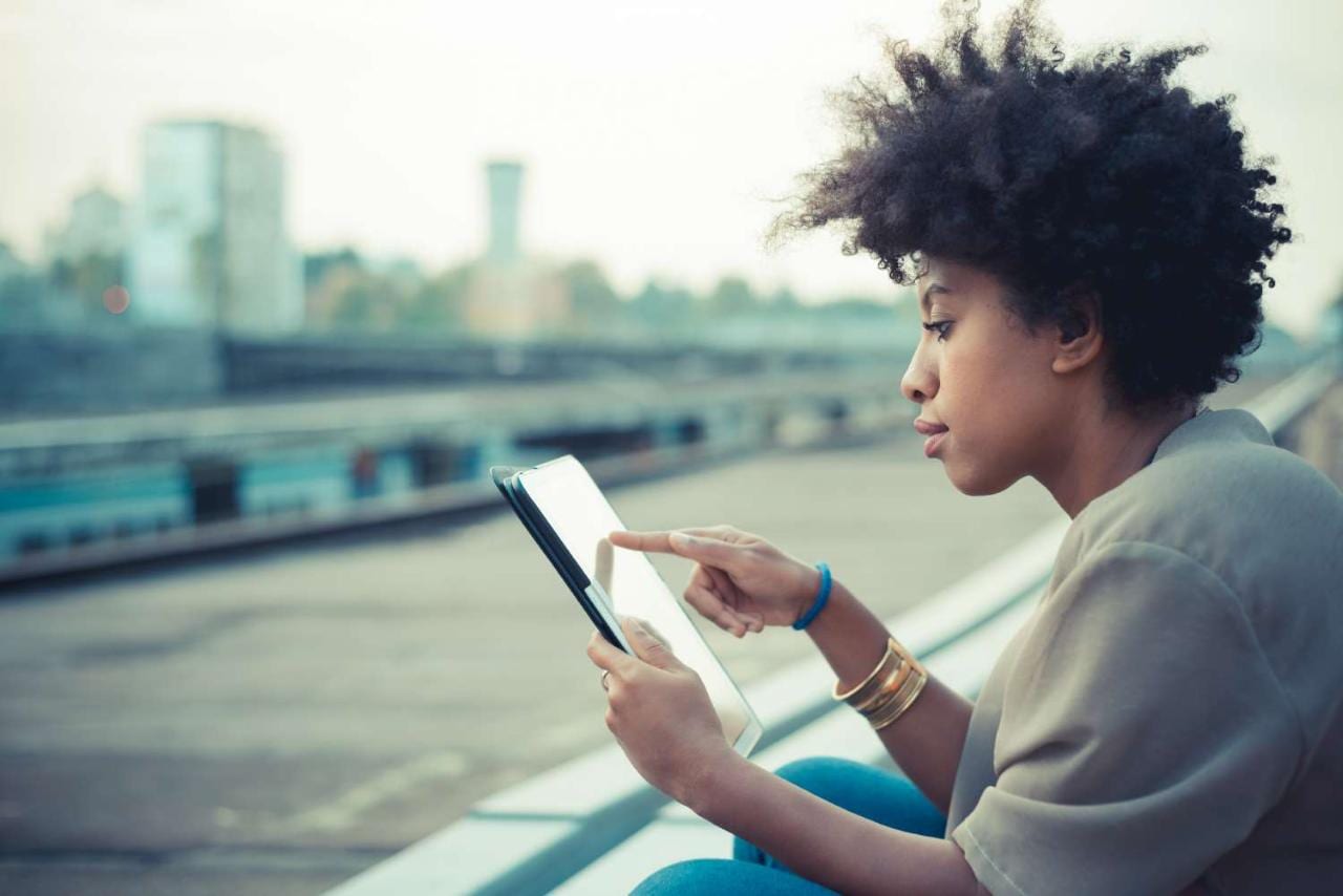Young woman using touchscreen on digital tablet on city rooftop Young woman using touchscreen on digital tablet on city rooftop