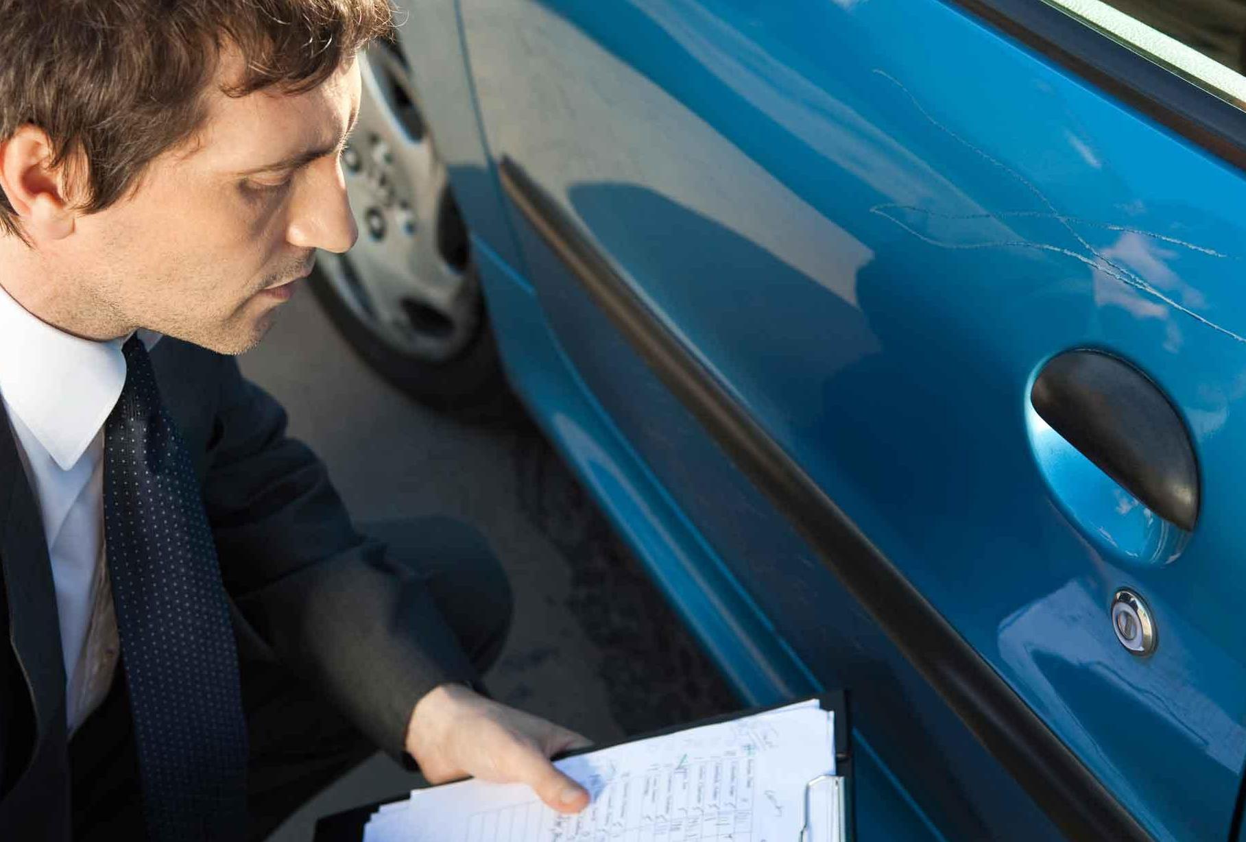 Man assessing and documenting damage to car