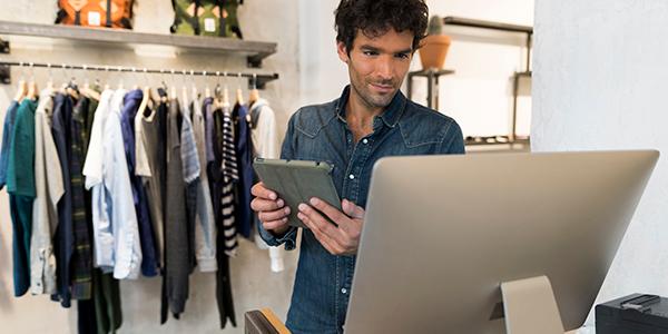 Building industry resilience | annual report Retail store owner looking at laptop with clothing rack in background