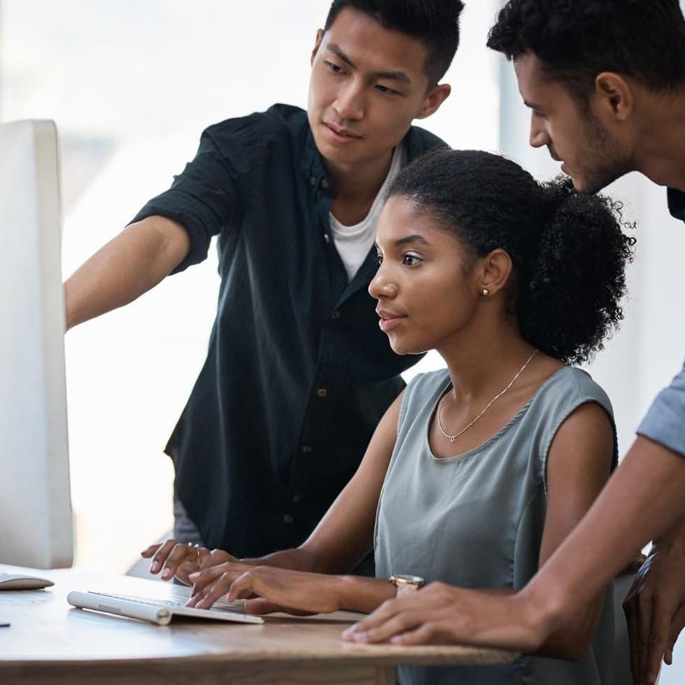 Three business professionals reviewing data on a desktop screen