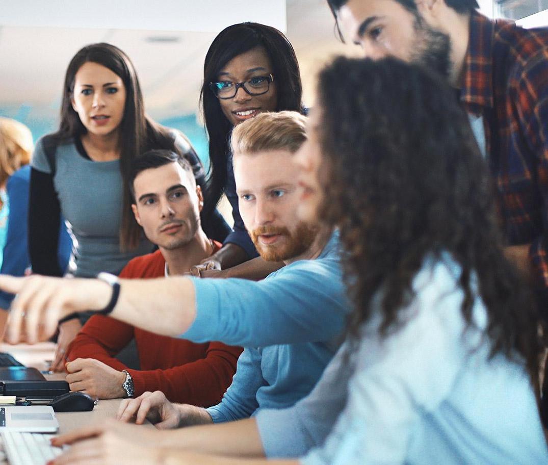Group of young coworkers having discussion around computer