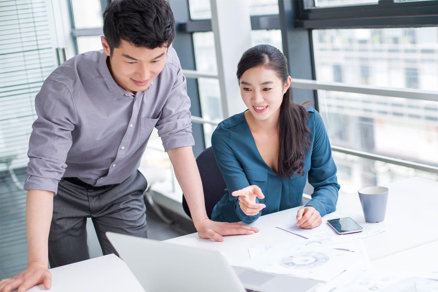 Young businesspeople discuss data on laptop