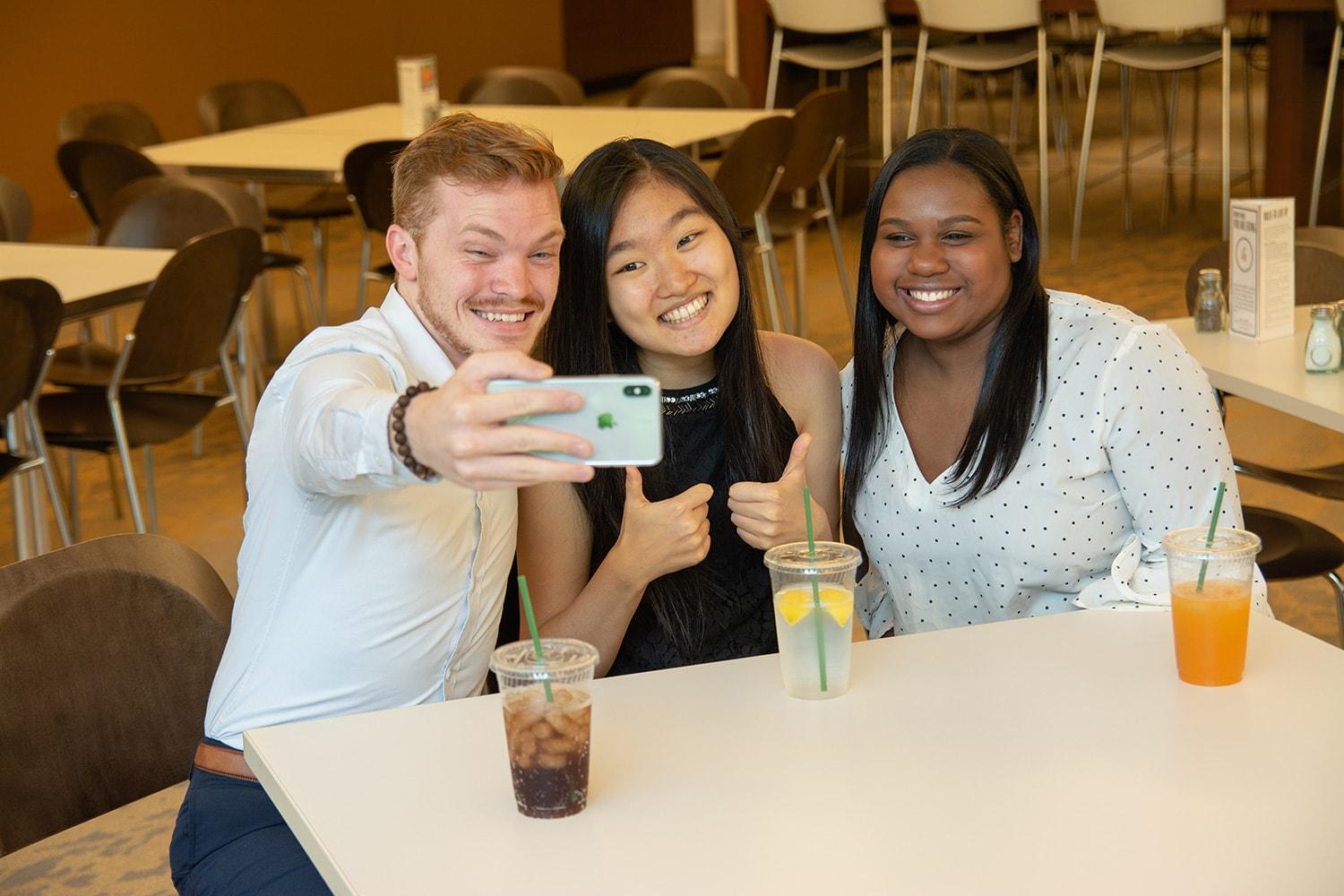 Three SAS employees taking a group photo in SAS cafe