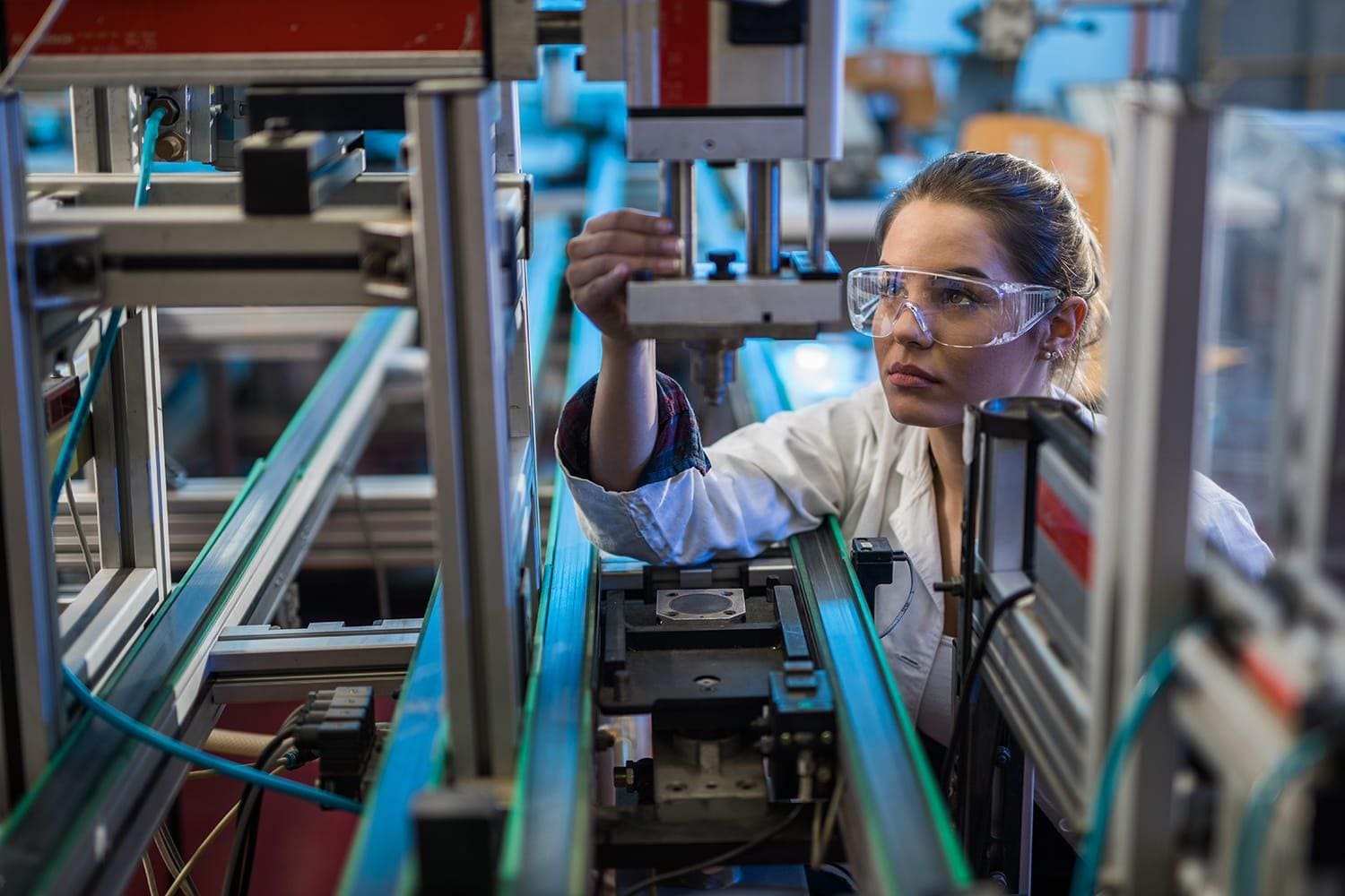 Femail technician analyzing machine part in manufacturing setting