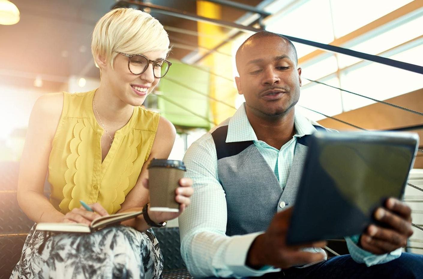 Two young business people with tablet device collaborating on a project