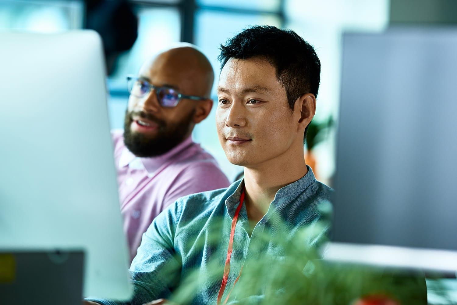 Office worker at desktop computer with colleague