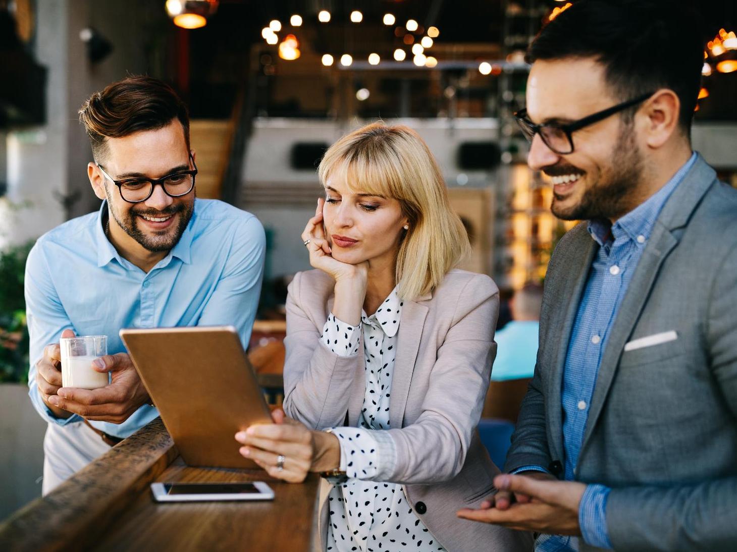 Three coworkers smiling reading tablet