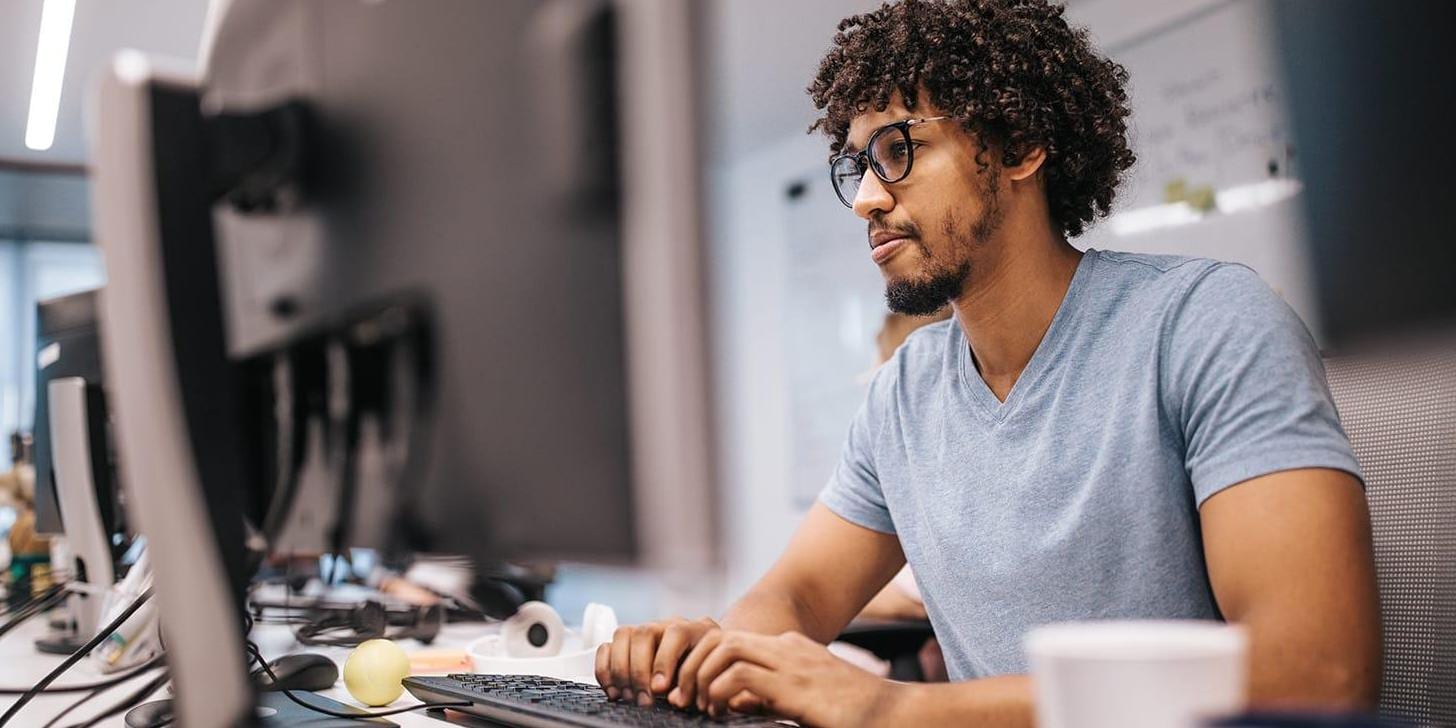 Young African American programmer working on desktop computer