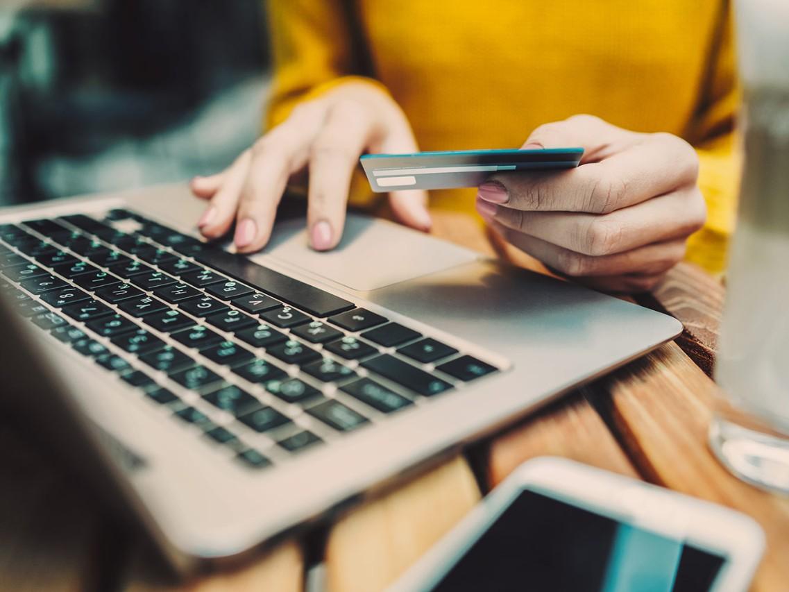 Woman sitting with laptop and bank card reviewing account
