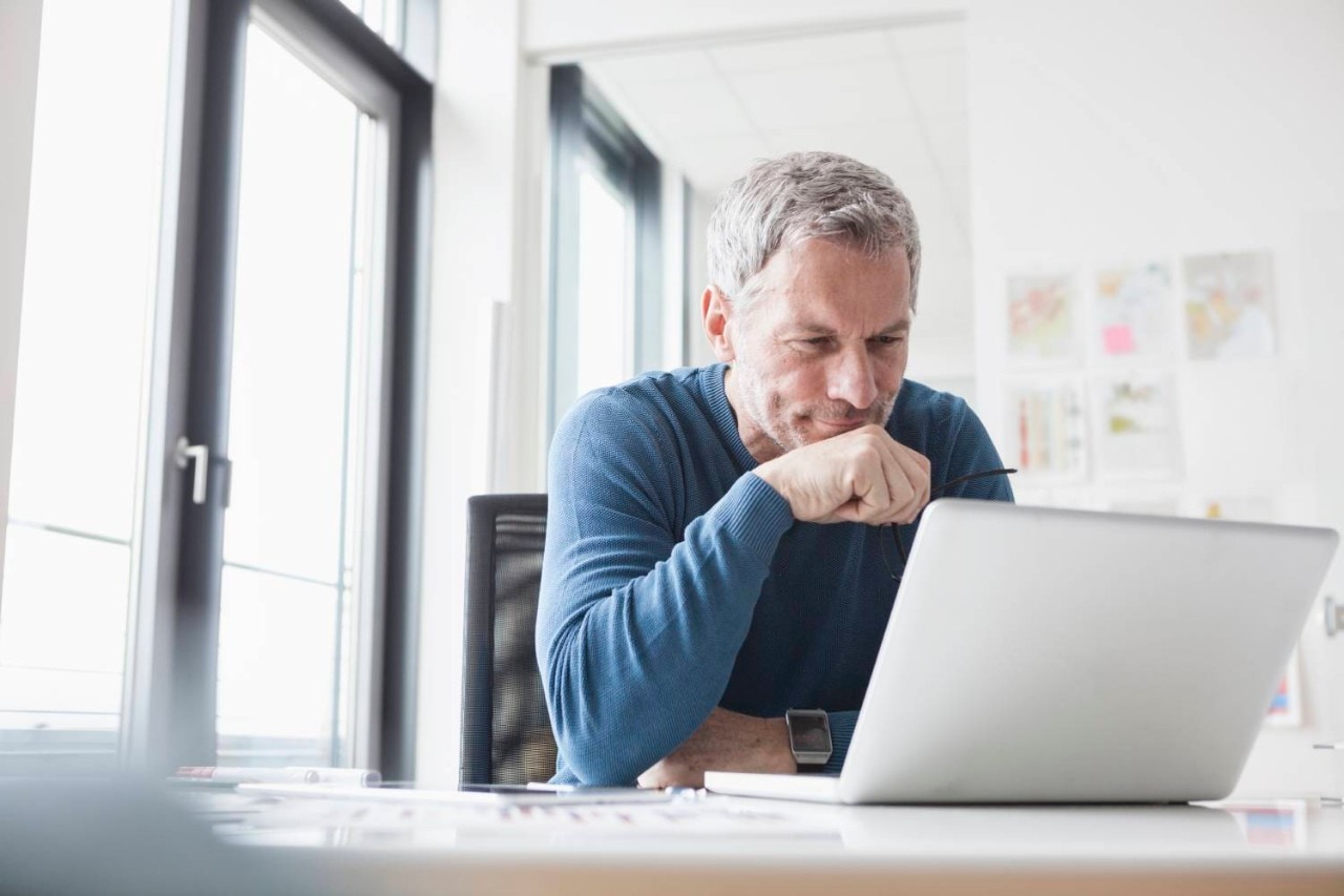 Mature man sitting in office using laptop 