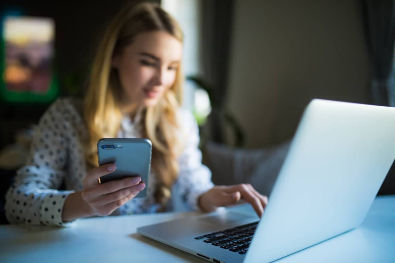 Woman using mobile phone and laptop