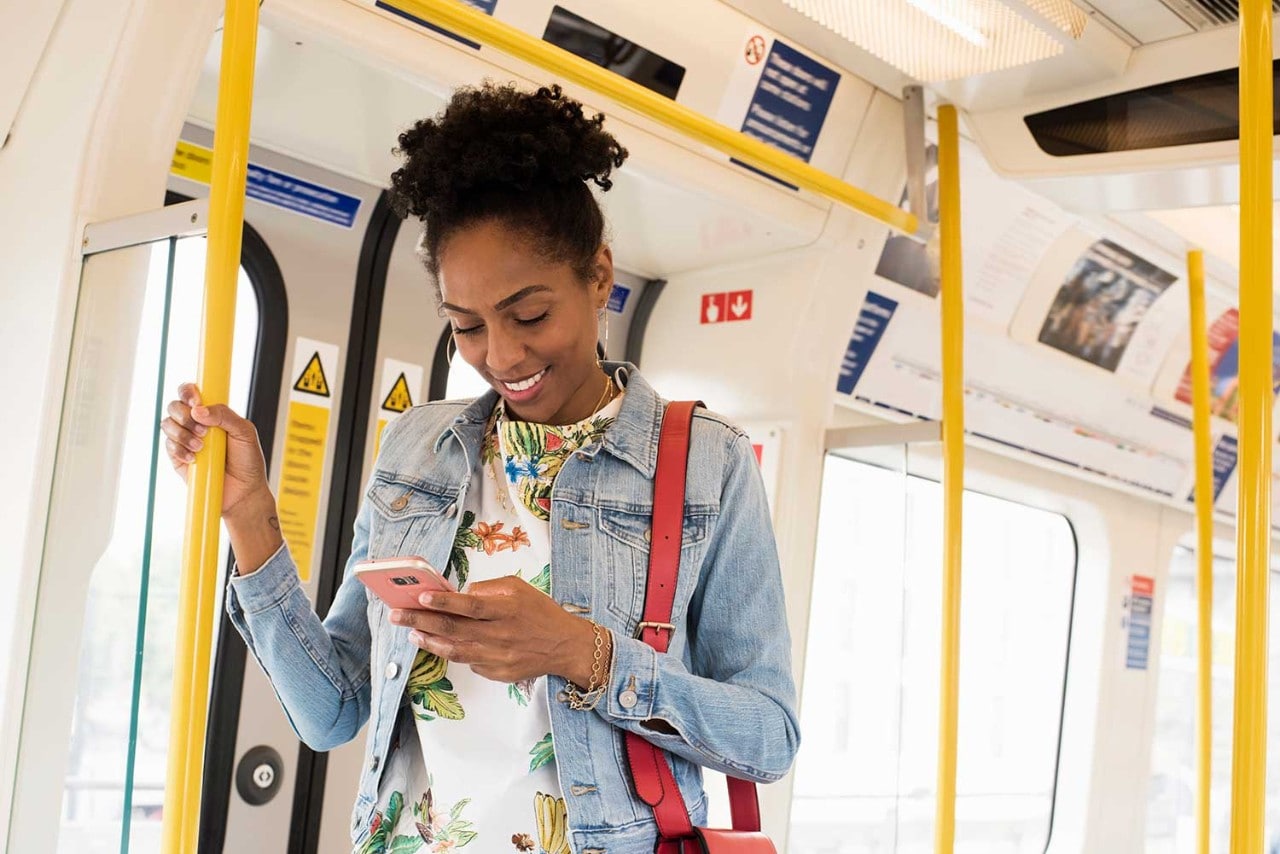 Woman smiling and looking at phone in train