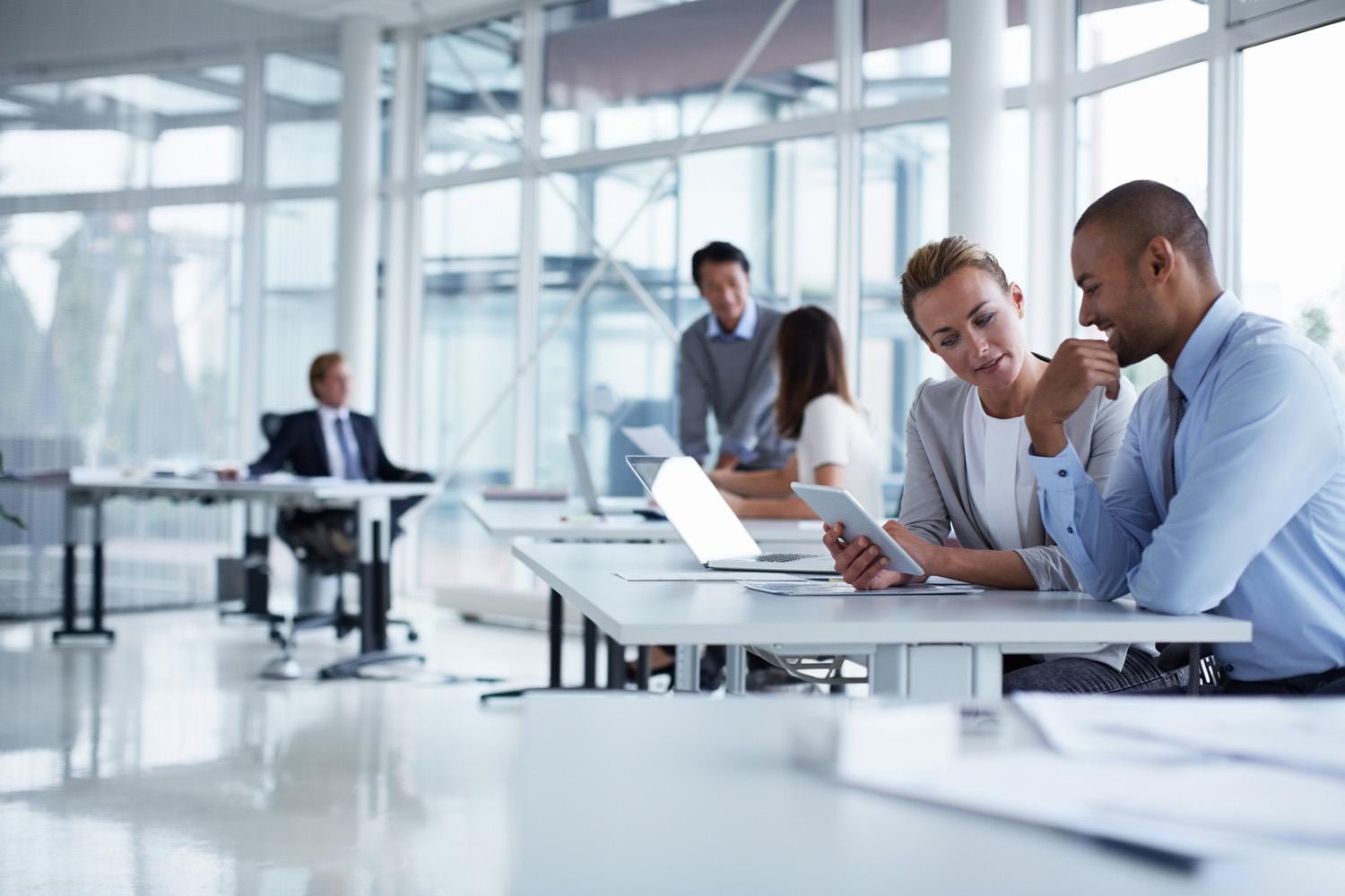 Business colleagues discussing over digital table at office desk Business colleagues discussing over digital table at office desk
