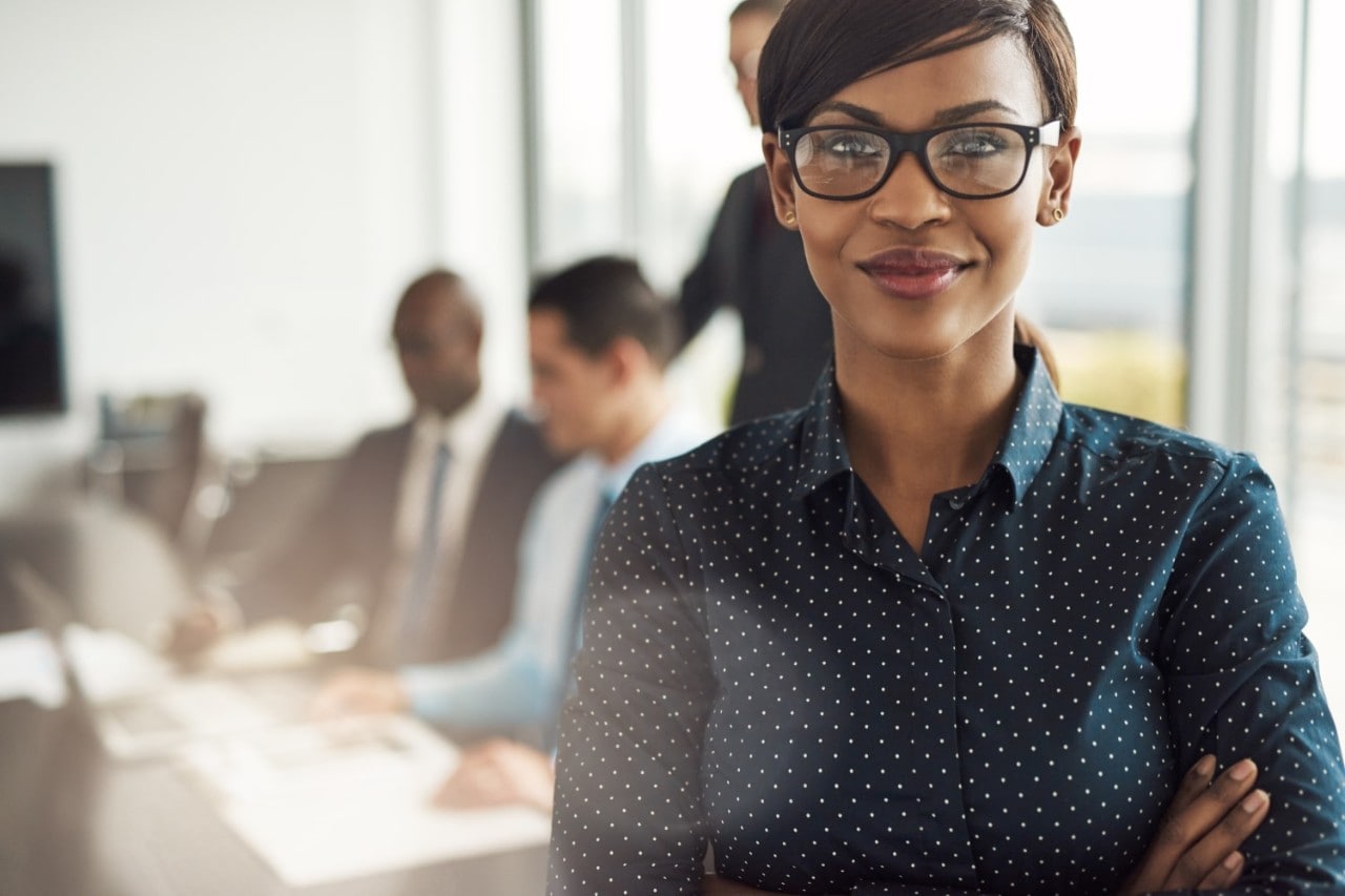 Woman With Glasses Blue Shirt With White Dots with Arms Crossed in Front Of the Meeting Table