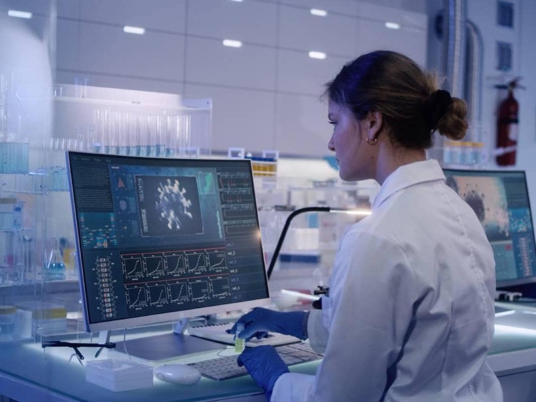 Woman in lab coat reviewing health data on computer screen