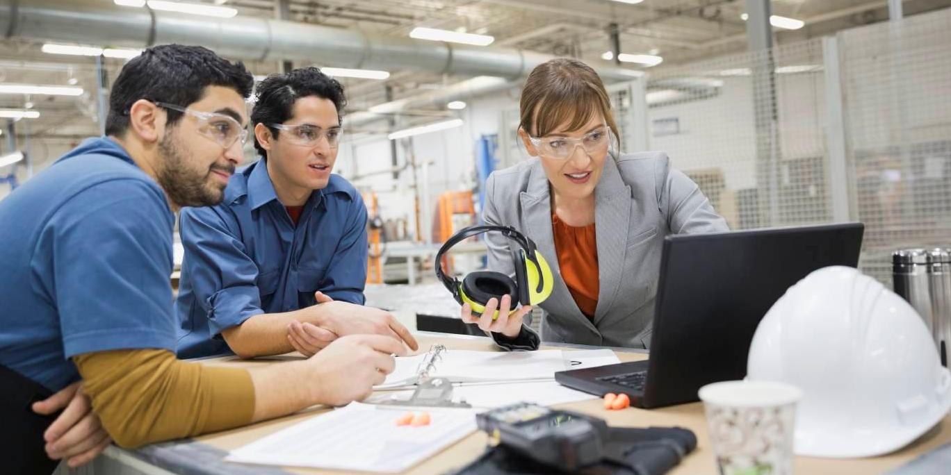 Enhancing productivity and performance | annual report Woman and two men in office setting looking at data on laptop