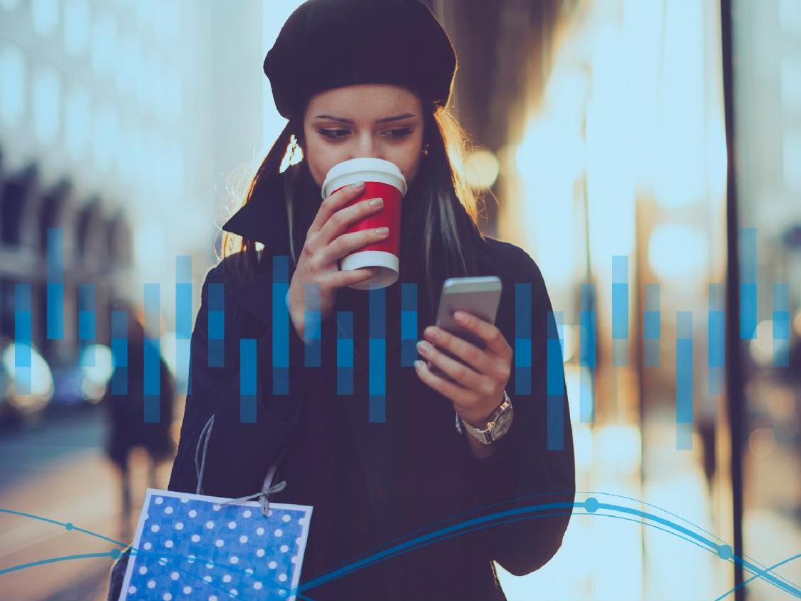 Woman walking down street with shopping bag and phone in hand