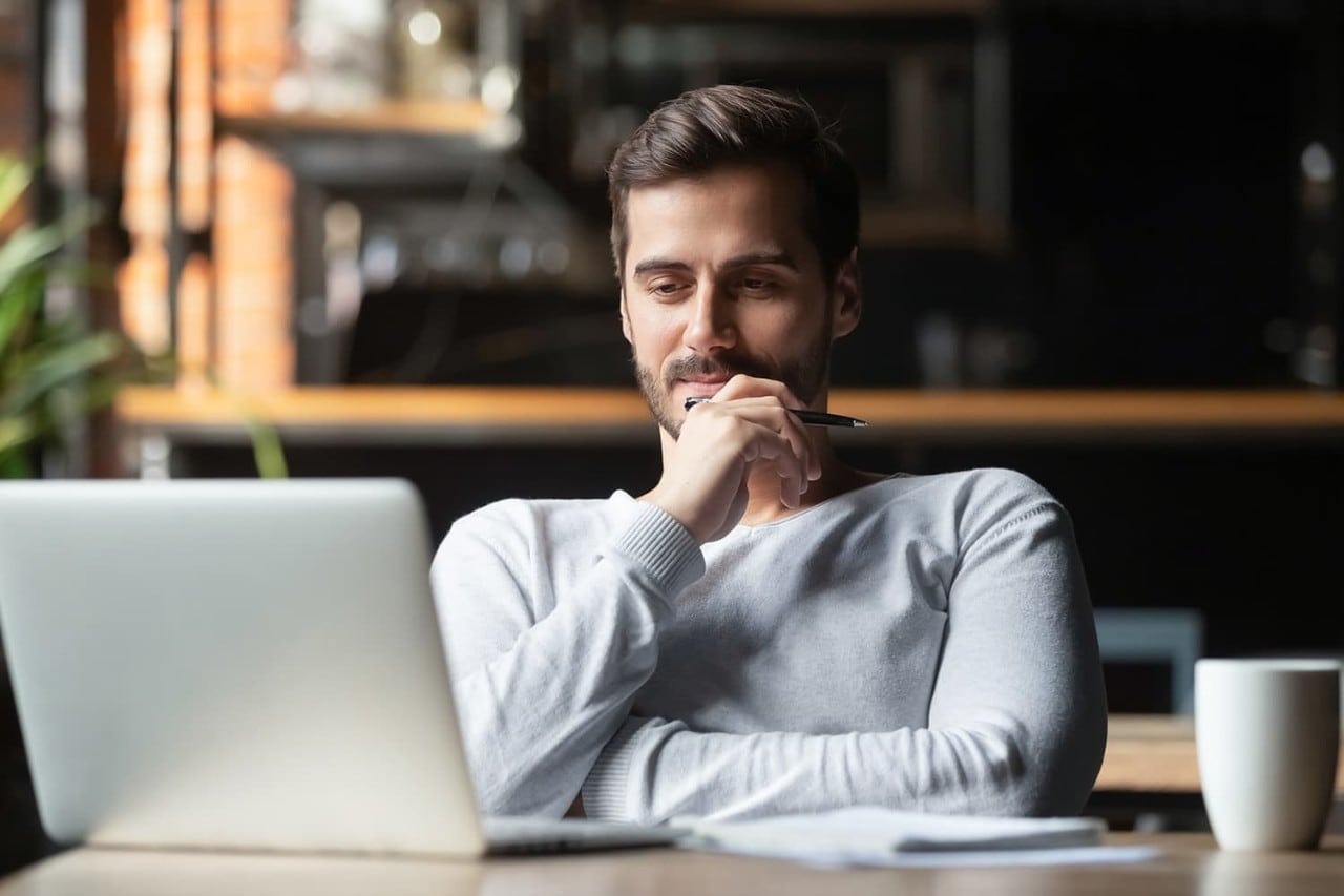 Man sitting down and gazing at laptop computer