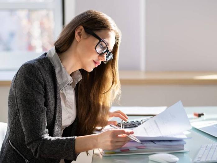 Woman sitting at desk looking through a stack of papers