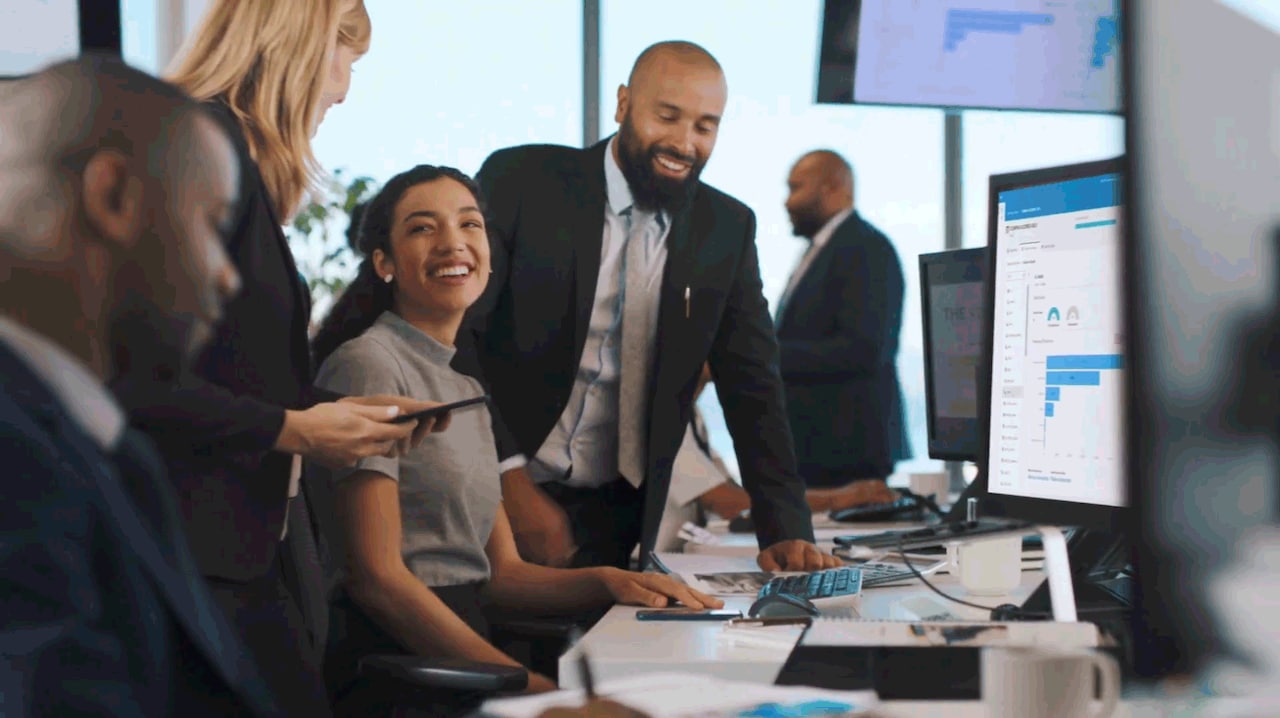 Coworkers chatting in front of computer with data on the screen