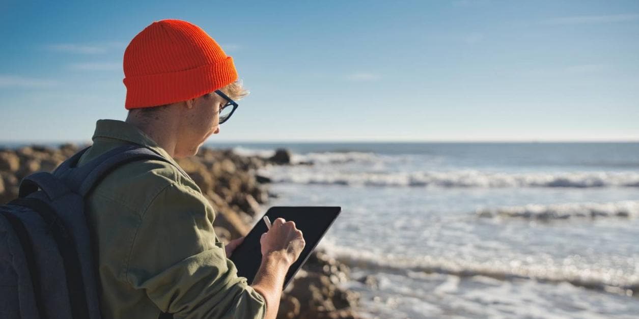 Improving the human condition | annual report Person working on mobile device at ocean