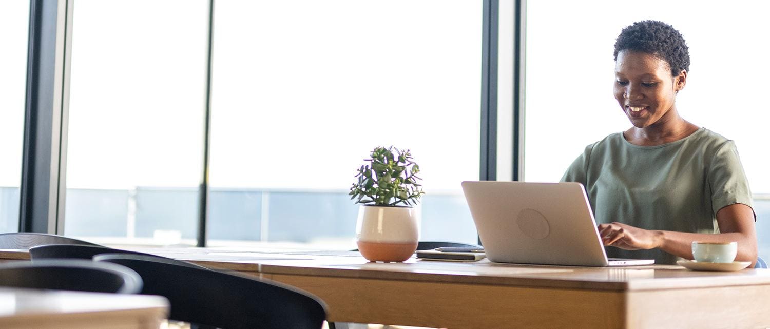 Woman at desk by a window using laptop Woman at desk by a window using laptop