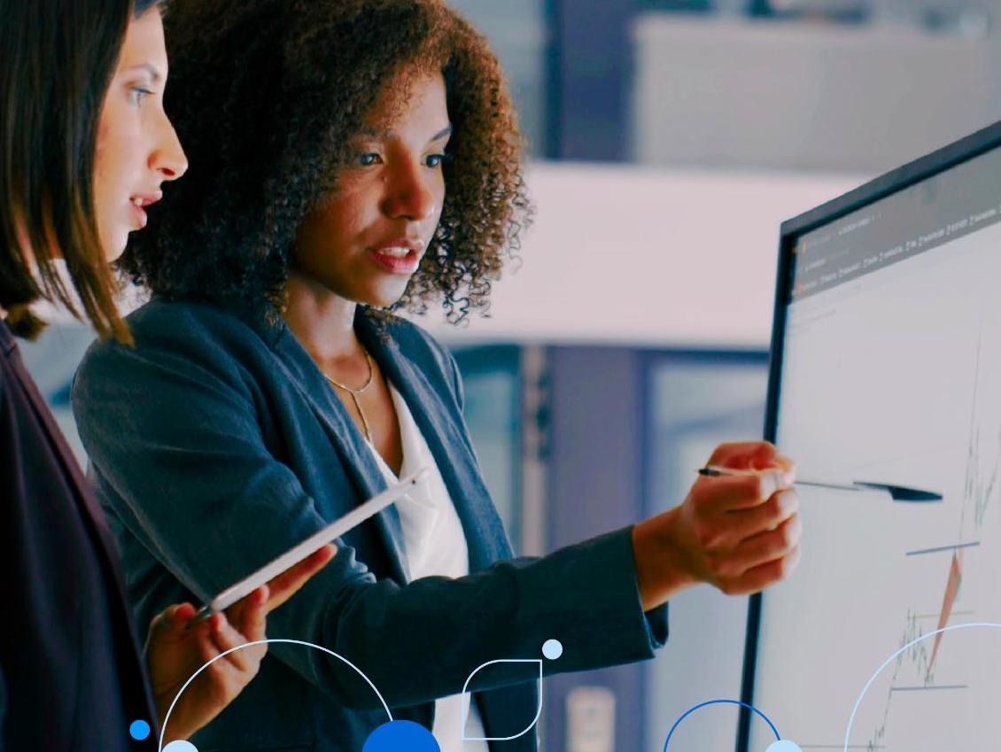 Two female coworkers viewing chart on desktop monitor